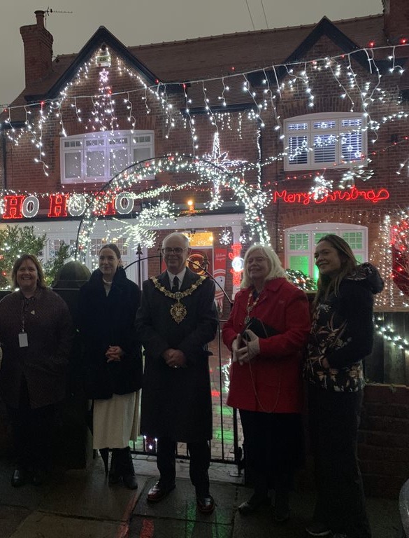 Wirral's Mayor and Mayoress outside a house in Oxton decorated with lights for Christmas. They are joined by a local resident and staff from The Hive Youth Zone.