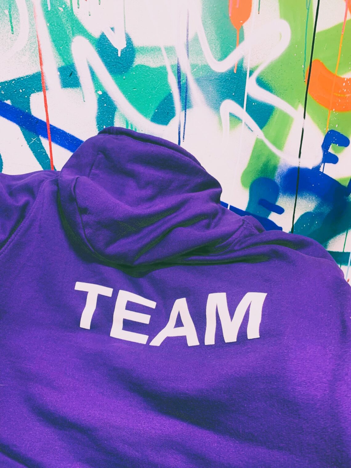 A purple hoodie with the word Team written on it in white letters